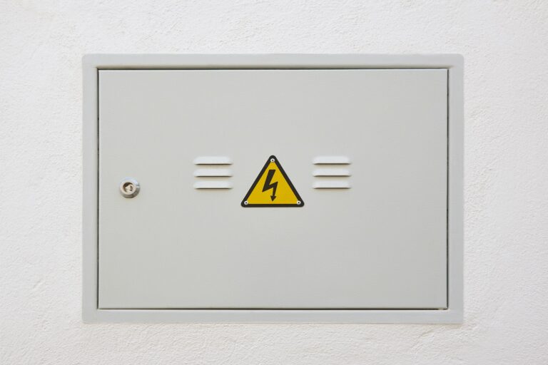 Electric meter box metallic door and white wall. Warning